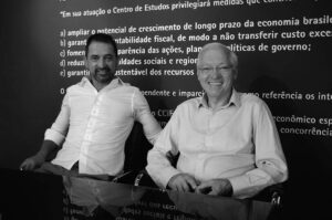 Dois homens de camisa social branca em frente a um painel com frases sobre o CCiF