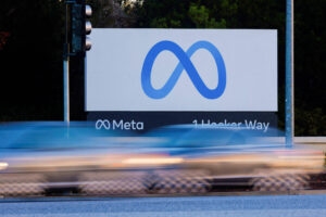 A imagem mostra uma placa da empresa Meta, com o logotipo em forma de infinito em azul. Abaixo do logotipo, está escrito