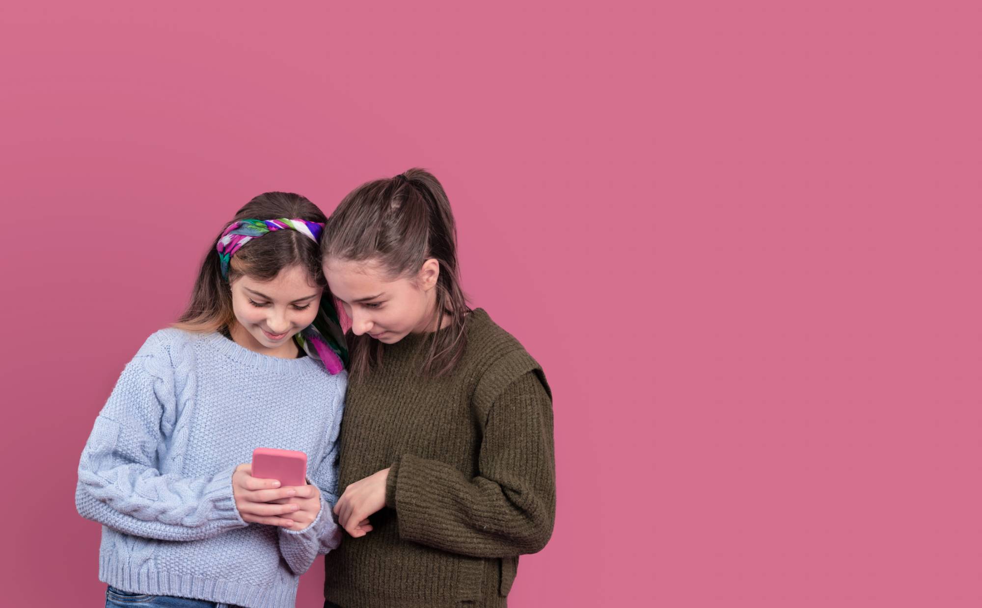 Happy girls browsing smartphone together