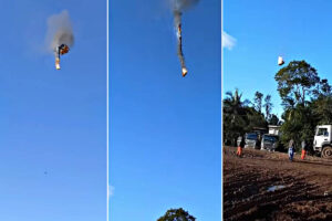 A imagem mostra uma sequência de três fotos de um objeto em chamas caindo do céu. O objeto parece ser um veículo ou uma estrutura, e está emitindo fumaça. No fundo, há um céu azul claro e, na parte inferior da imagem, algumas pessoas observam a cena em uma área de terra batida, com árvores e veículos ao fundo.