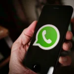 Pessoa segurando um celular aberto na página inicial do WhatsApp.