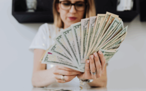 Mulher segurando notas de dólar americano, simbolizando a queda do dólar e as oportunidades para morar nos Estados Unidos com assessoria da SG Global Group.