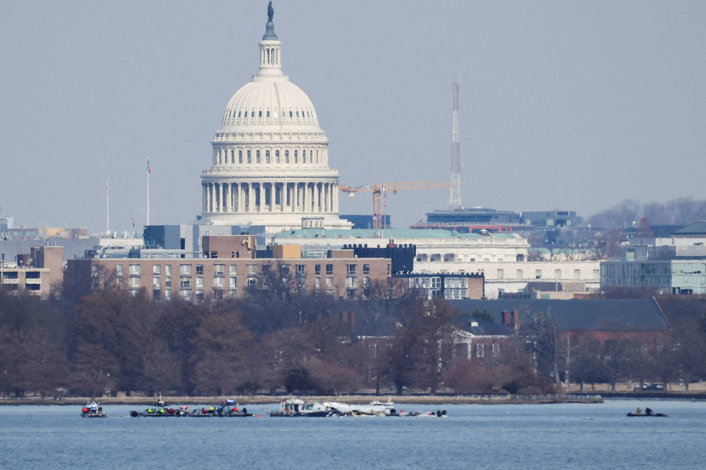 A imagem mostra o Capitólio dos Estados Unidos ao fundo, com sua cúpula branca e detalhes arquitetônicos visíveis. Em primeiro plano, há um corpo d