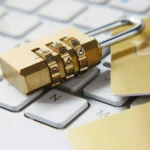 Segurança digital sendo reproduzida por um cadeado fechado em cima de um teclado e cartões de crédito.