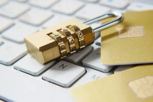 Segurança digital sendo reproduzida por um cadeado fechado em cima de um teclado e cartões de crédito.