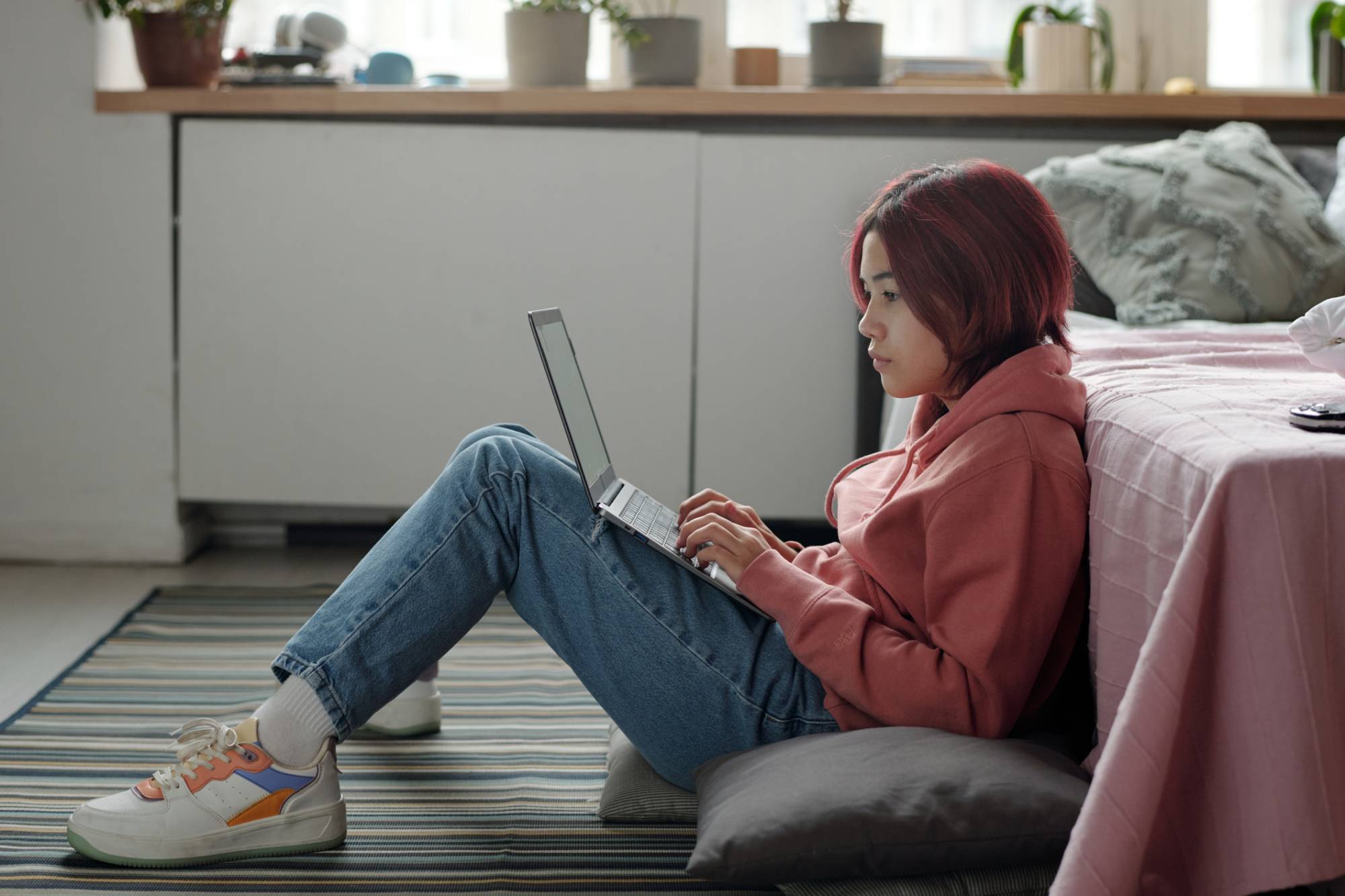 Schoolgirl with laptop sitting on cushions