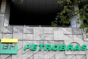 A imagem mostra o logotipo da Petrobras em uma parede de concreto. O logotipo é composto por um retângulo amarelo com as letras