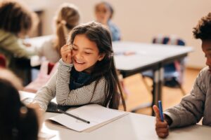 Small girl laughs happily in a primary school class.