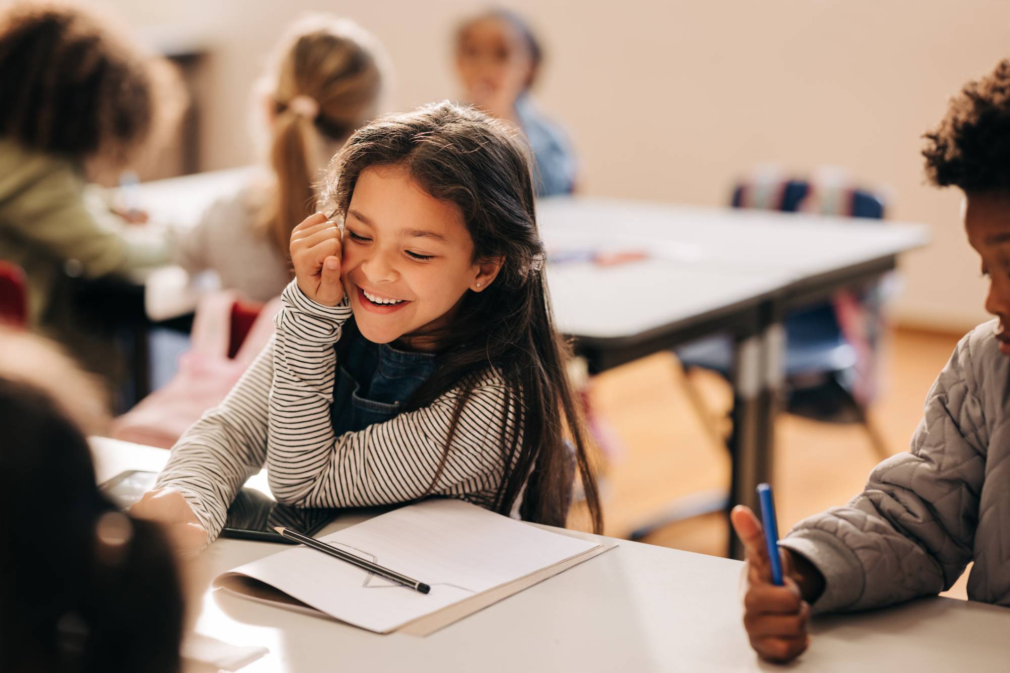 Small girl laughs happily in a primary school class.