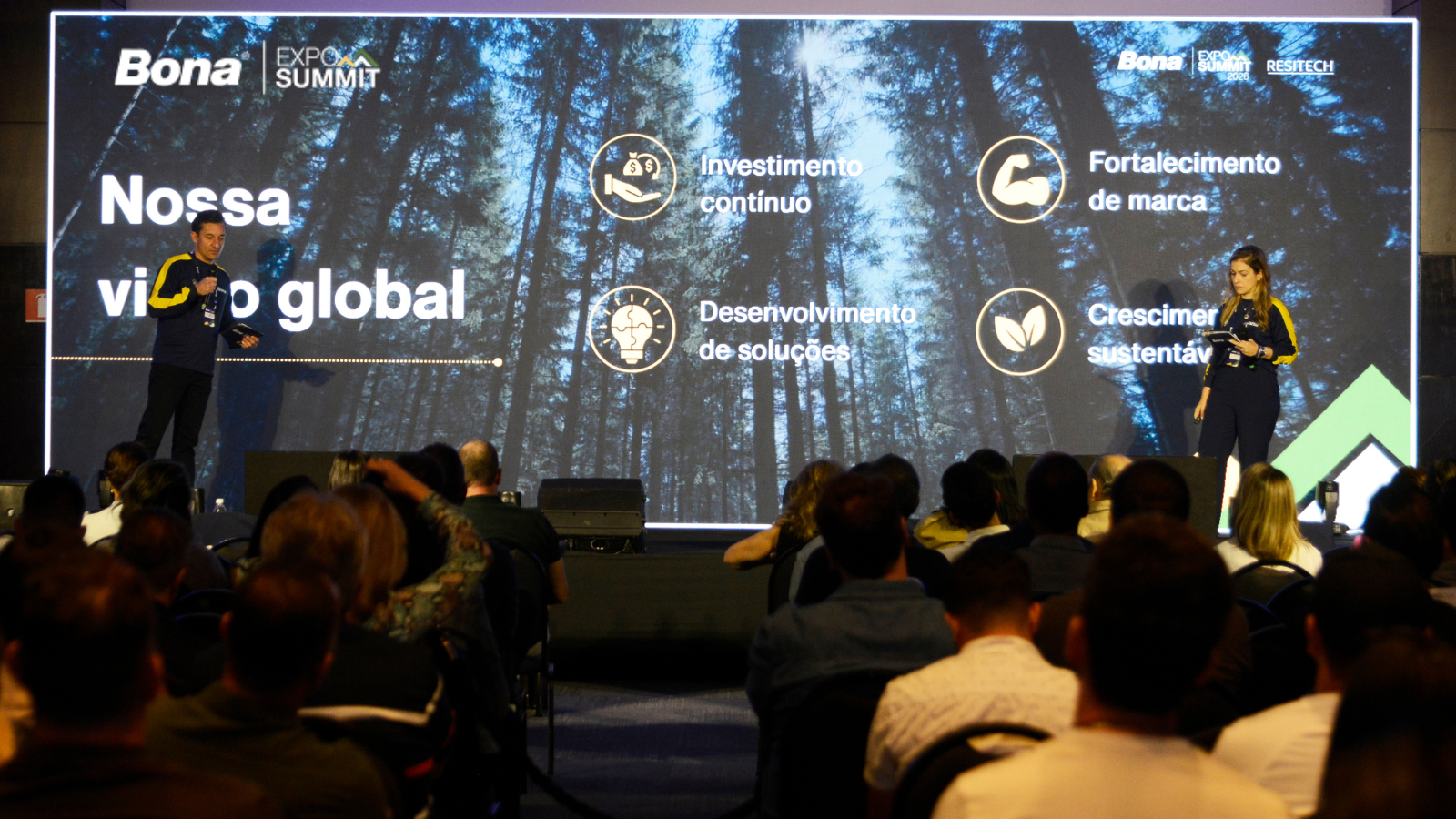 Flavia Felgueiras e Felipe Ferrerinha no palco do Bona Expo Summit 2026 apresentando visão estratégica da Bona para o mercado de pisos.