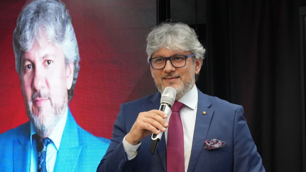 Luciano Menezes, CEO da B2WE Brasil, durante evento empresarial, discursando sobre Reforma Tributária e risco fiscal estratégico.