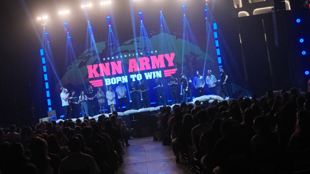 Palco da KNN Convention 2026 Born To Win com público lotado e equipe no palco durante encerramento do evento