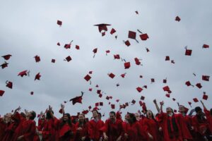 Students toss their mortarboards in the air at a commencement ceremony.
