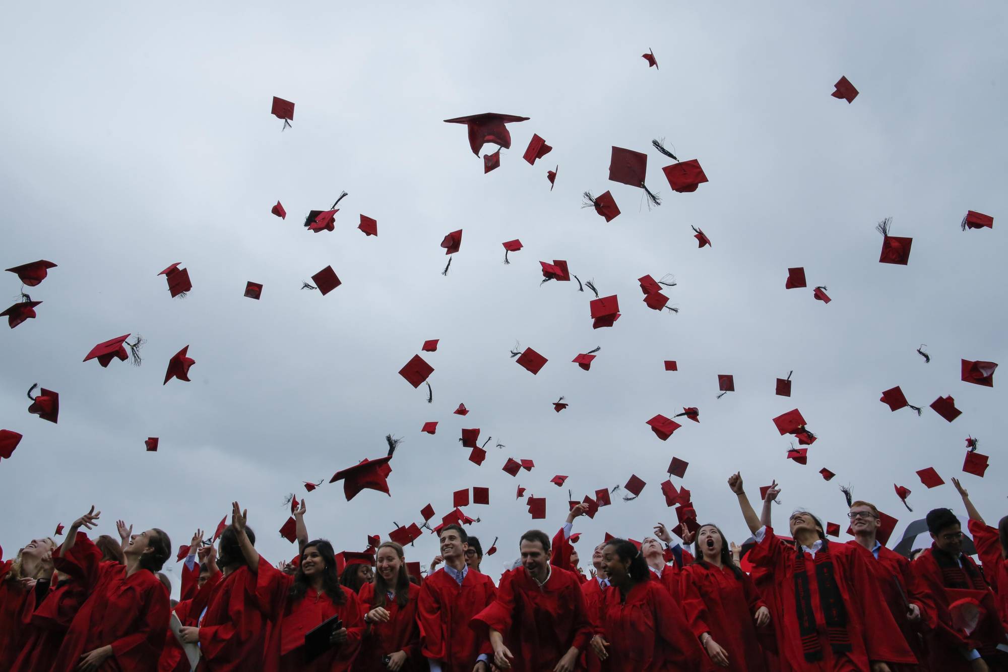 Students toss their mortarboards in the air at a commencement ceremony.