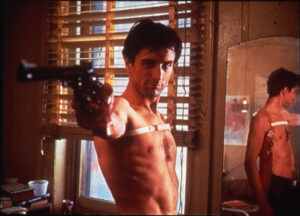 Robert De Niro como Travis Bickle apontando arma em cena clássica do filme Taxi Driver de Martin Scorsese