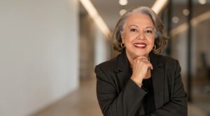Myrinha Vasconcellos em ambiente corporativo, representando liderança, experiência e confiança.